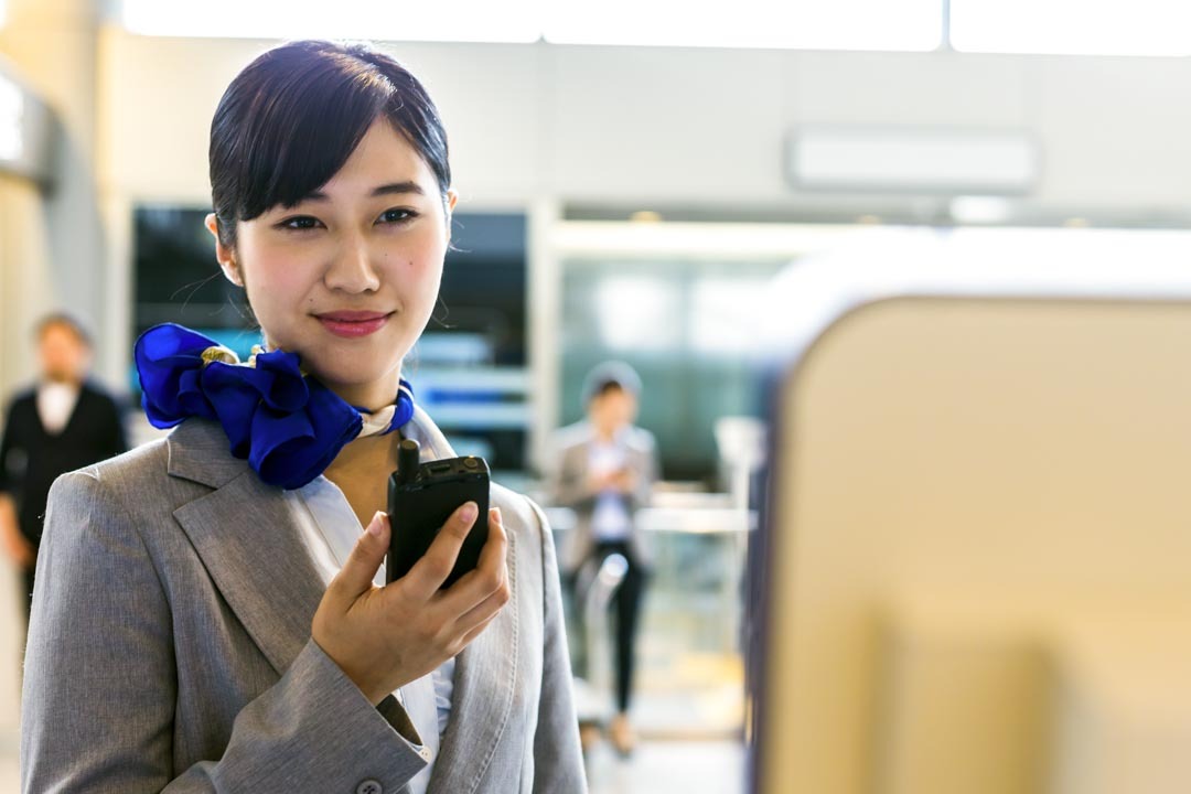 female airport worker holding two-way radio